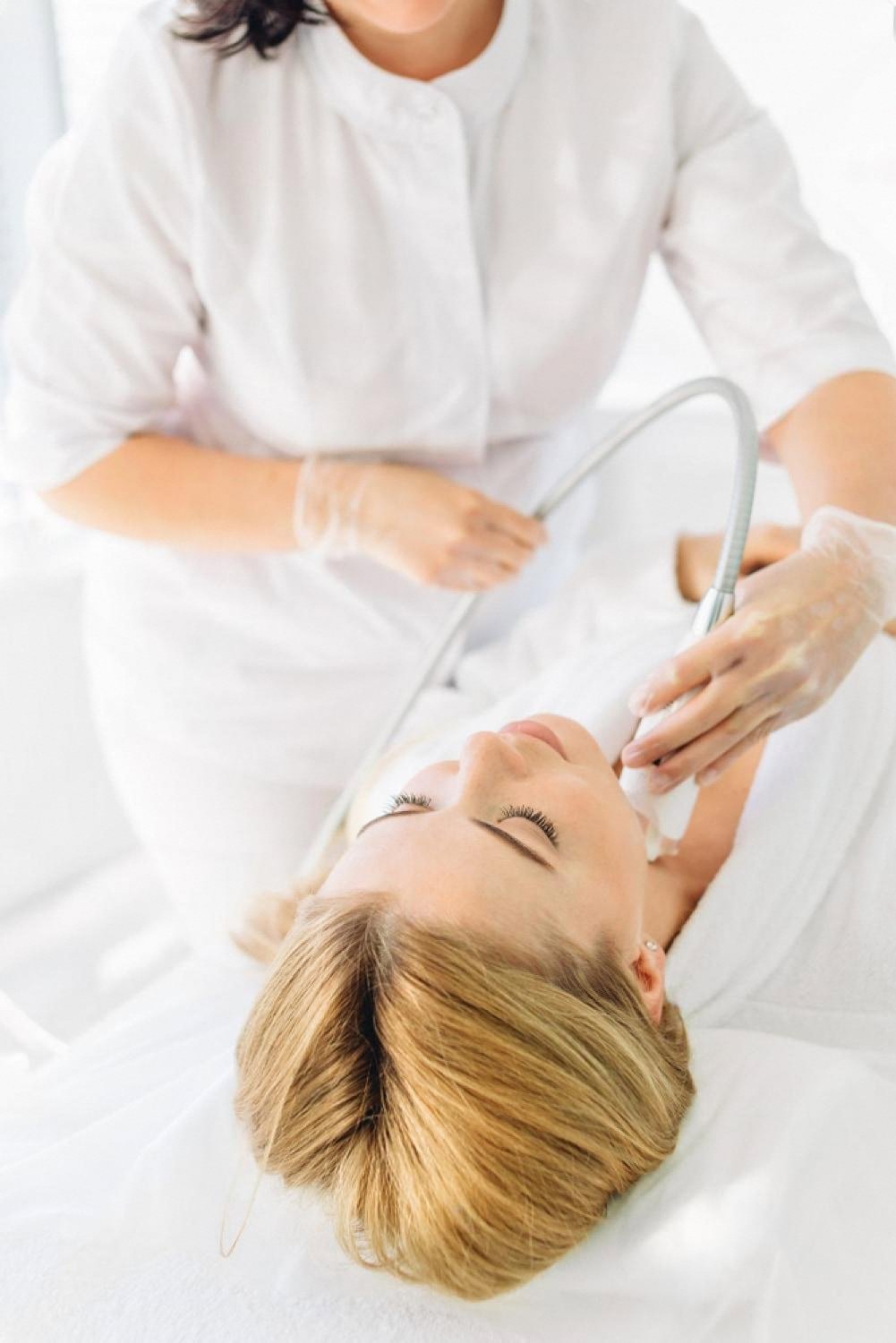 Cosmetologist performing a radiofrequency lifting hardware procedure on a client's face